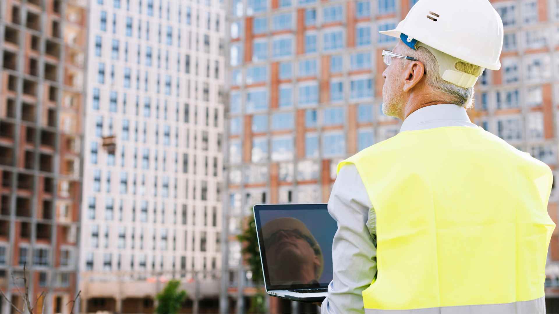 Engineer holding laptop in front of building - Nexacu